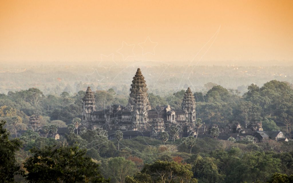 Torres do templo de Angkor Wat acima da selva enevoada ao amanhecer difuso