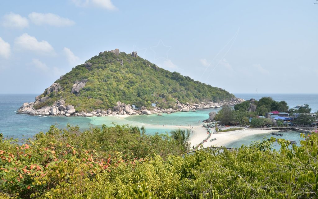 Banco de areia a ligar ilhas de granito arborizadas, águas turquesa rasas, guarda-sóis e cais em Koh Nang Yuan, Tailândia