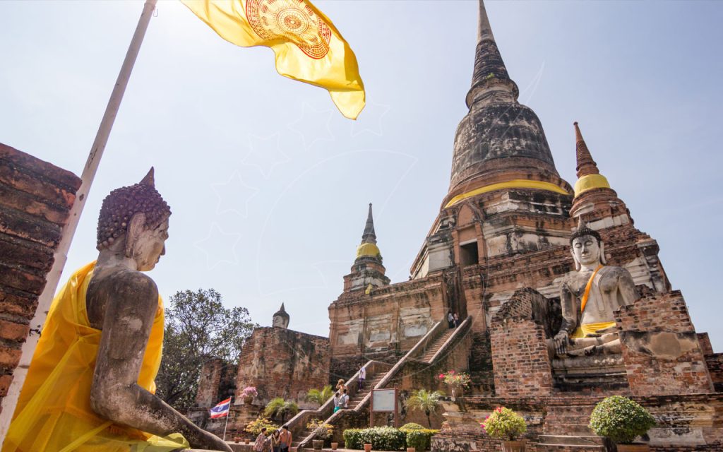 Estátuas de Buda sentado com faixas amarelas diante de grande estupa de tijolo e bandeira amarela, Ayutthaya, Tailândia