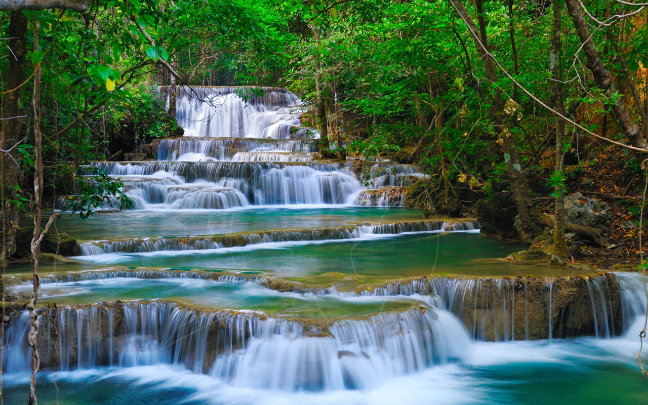 Cascata turquesa em vários patamares sobre terraços de calcário em floresta tropical densa