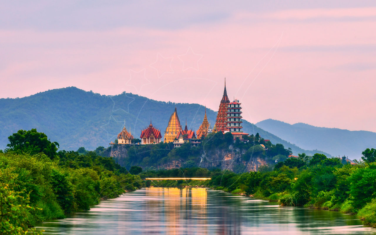 Templo tailandês dourado e pagode de vários andares numa colina calcária sobre um rio calmo ao crepúsculo rosa
