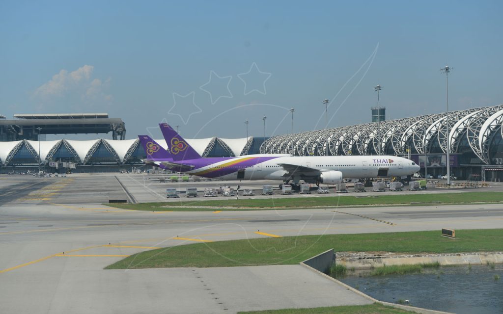 Thai Airways widebody jet parked at Suvarnabhumi Airport terminal in Bangkok under a clear blue sky