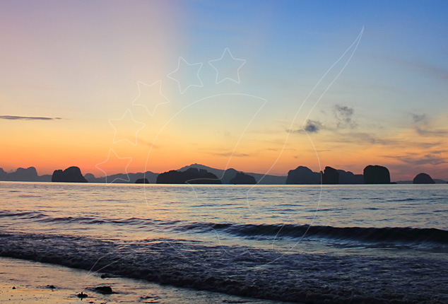 Pôr do sol sobre mar calmo com ilhas cársicas calcárias em silhueta no horizonte e pequenas ondas a chegar à costa