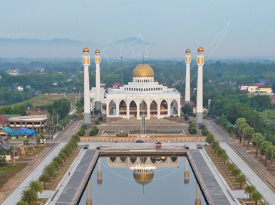 Vista aérea de mesquita branca com cúpula dourada e quatro minaretes espelhados num longo lago com palmeiras
