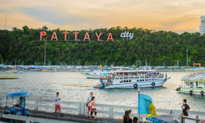 Letreiro vermelho PATTAYA CITY na encosta sobre a baía de Pattaya com barcos, lanchas e pessoas no passeio da praia