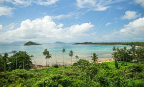 Vista elevada sobre uma baía tropical com água turquesa, palmeiras, praia de areia e pequenas ilhas ao largo