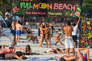 Praia cheia com faixa colorida da Full Moon Beach, banhistas e nadadores em águas tropicais rasas