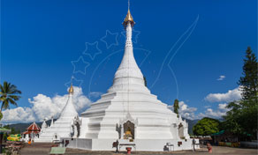 Chedi budista branco com pináculo dourado num templo no topo de uma colina sob céu azul, Mae Hong Son, Tailândia