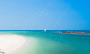 Praia de areia branca com água turquesa rasa, um pequeno veleiro branco e um ilhéu rochoso sob céu azul límpido