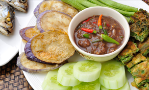 Nam prik tailandês numa tigela branca com peixe frito, beringela, pepino, feijão-verde e omelete de ervas