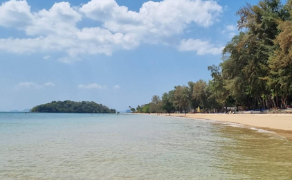 Praia tropical intocada com água turquesa pouco profunda, areia branca e palmeiras sob céu azul