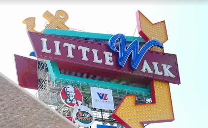 Letreiro de neon vintage Littlwalk em turquesa e roxo num edifício de tijolo
