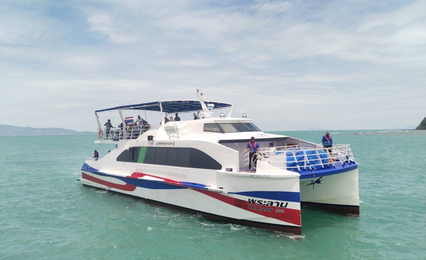 Ferry catamarã rápido branco "Lomprayah 8" com faixas vermelhas e azuis no casco em mar turquesa calmo, passageiros no deck superior