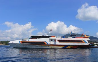 Ferry catamarã rápido branco com faixas vermelhas, laranja e azuis ancorado em mar azul calmo perto de colinas verdes