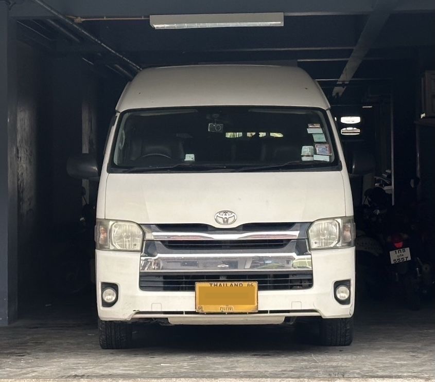 Carrinha Toyota Hiace branca de tejadilho alto vista de frente numa garagem escura, matrícula amarela tailandesa