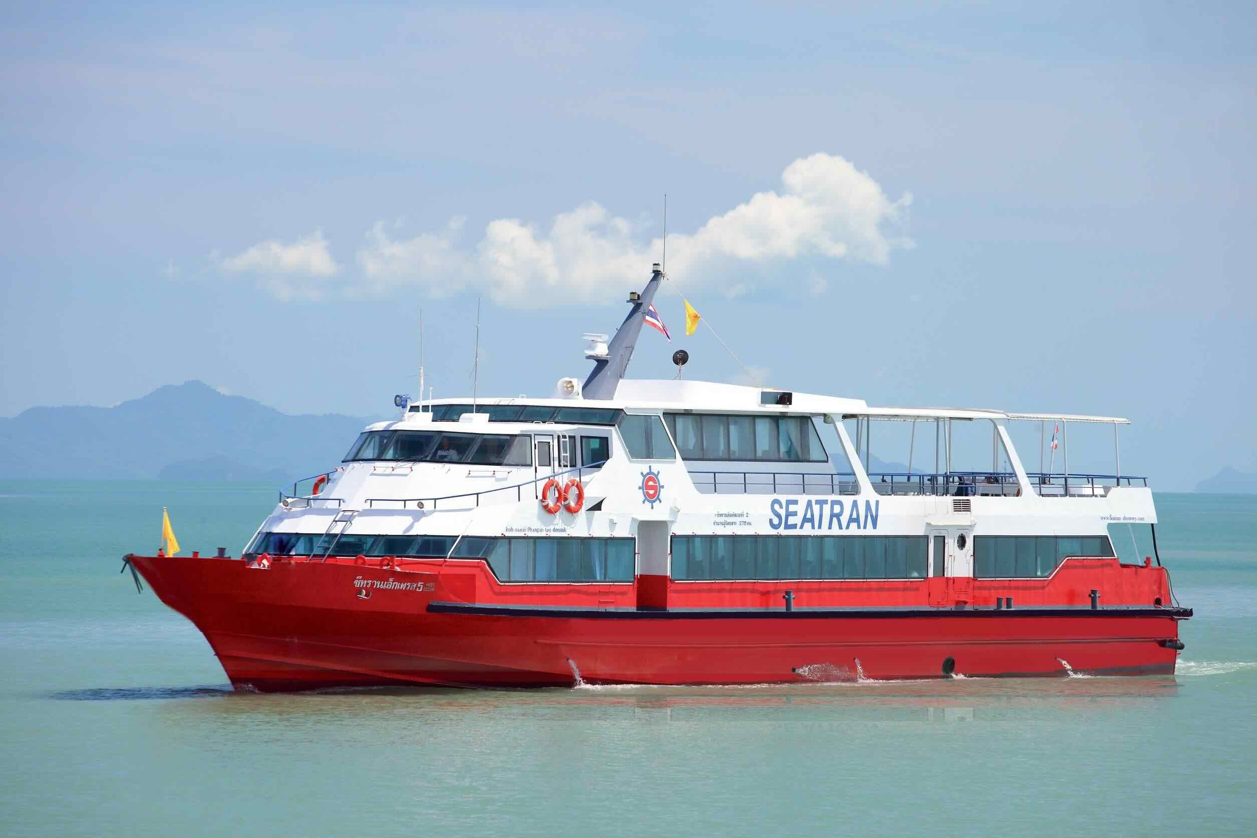 Ferry de passageiros Seatran vermelho e branco a navegar em mar verde calmo com colinas enevoadas atrás