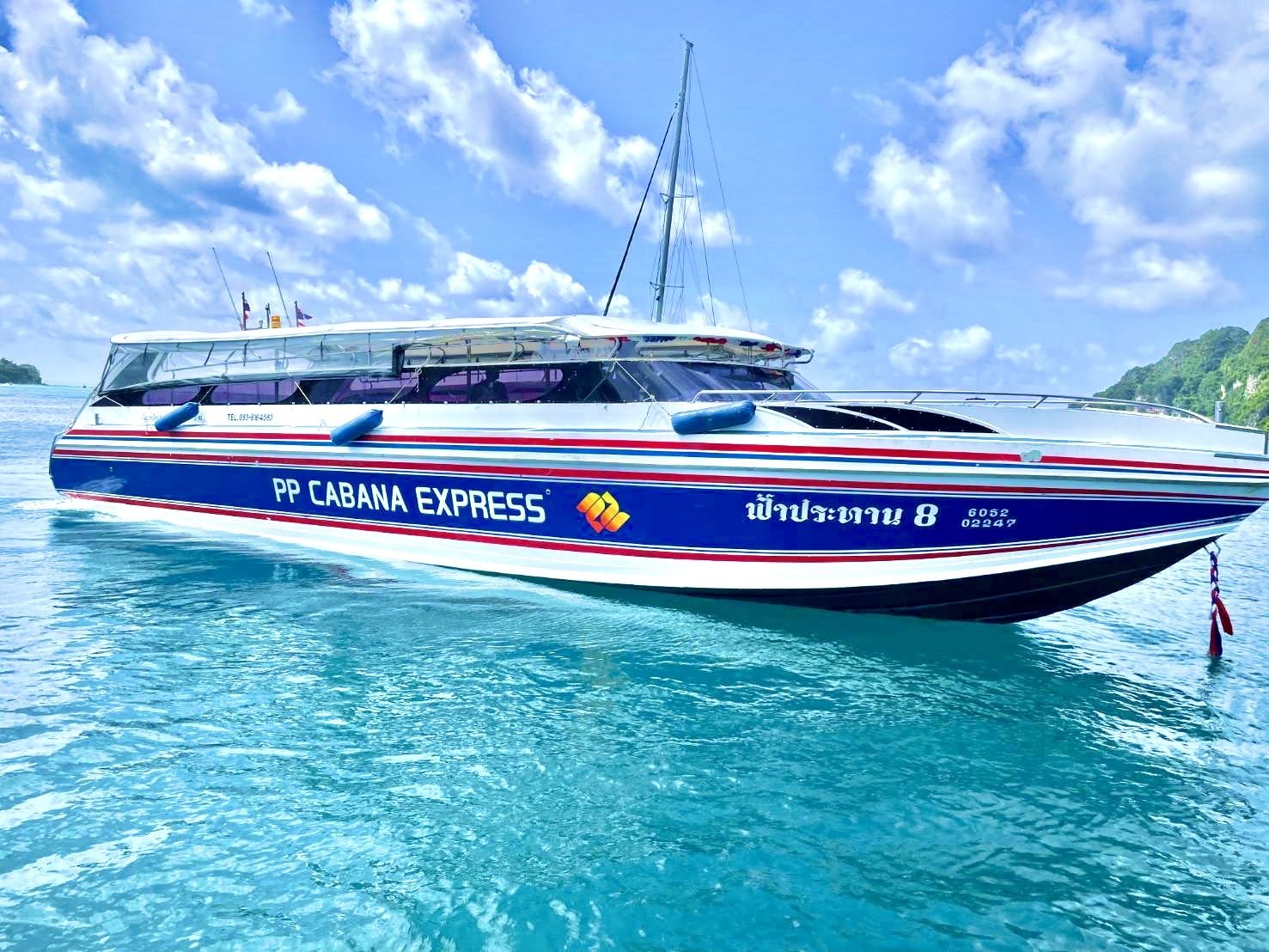 Lancha rápida azul e branca "PP Cabana Express" atracada em água turquesa cristalina junto a ilhas calcárias, Tailândia
